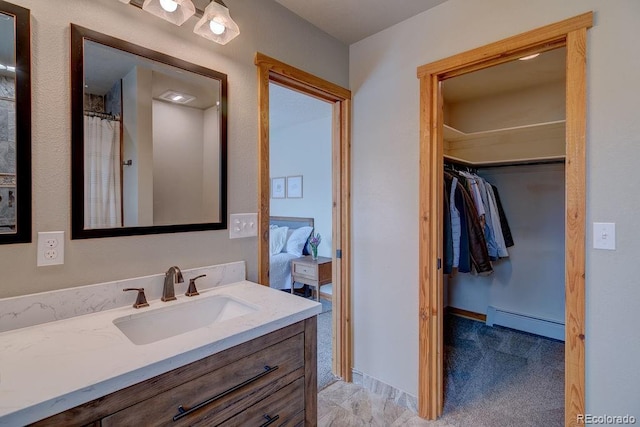 bathroom featuring a baseboard radiator, vanity, and a spacious closet