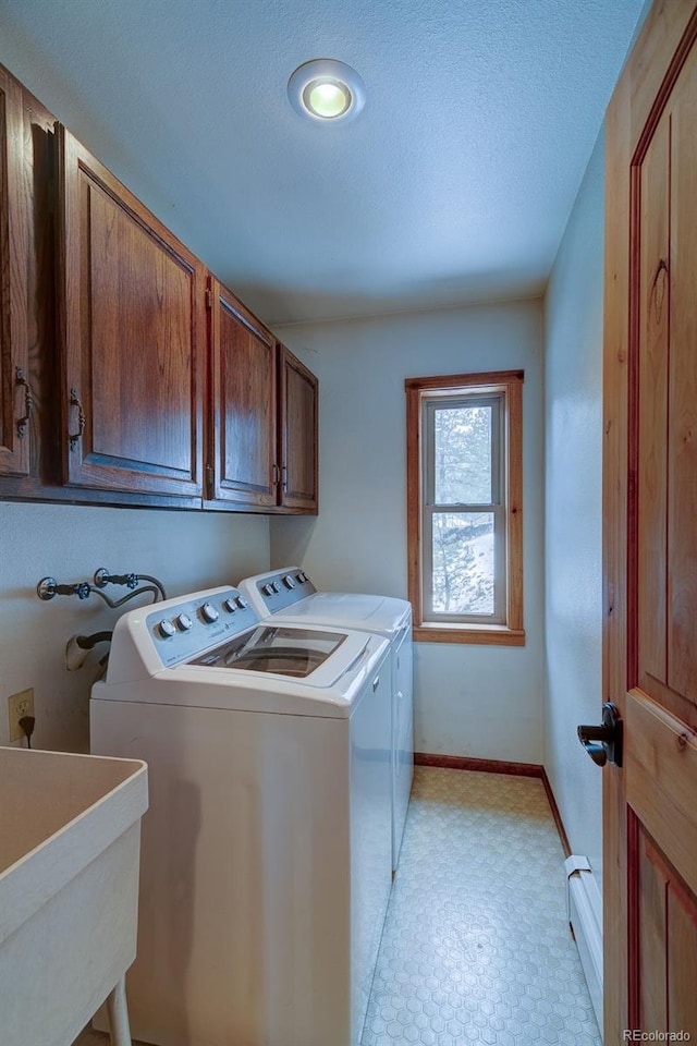 clothes washing area with independent washer and dryer, cabinet space, baseboards, a baseboard radiator, and light floors