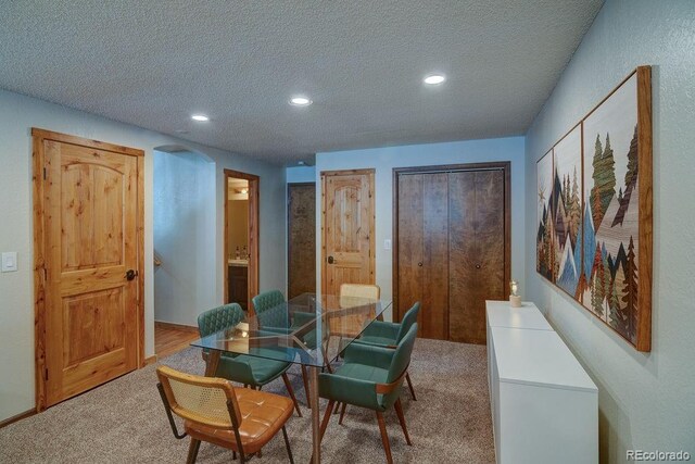 dining room with carpet flooring, a textured ceiling, recessed lighting, and arched walkways