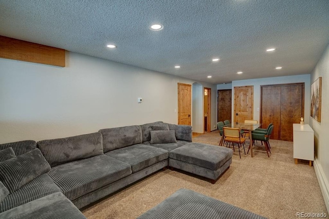 living area featuring recessed lighting, light carpet, and a textured ceiling