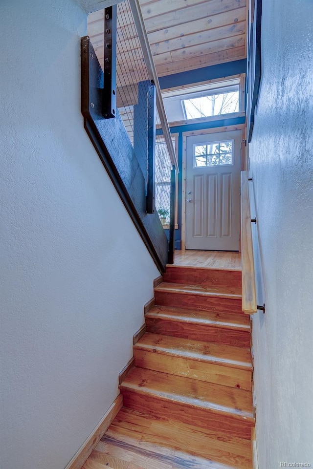 stairs featuring wood finished floors, baseboards, and a textured wall