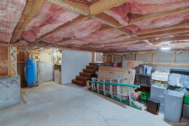 unfinished basement featuring a water pressure tank and stairs