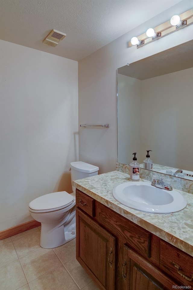 bathroom with toilet, vanity, tile patterned floors, and a textured ceiling