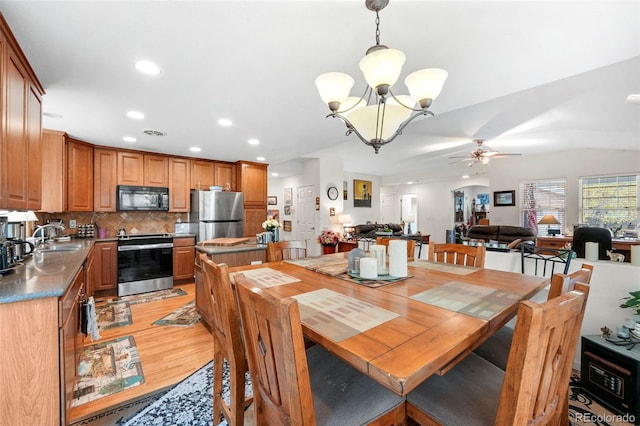 dining area featuring ceiling fan with notable chandelier, light hardwood / wood-style floors, and sink