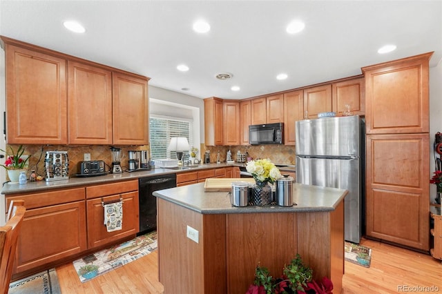 kitchen featuring a center island, light hardwood / wood-style floors, and black appliances