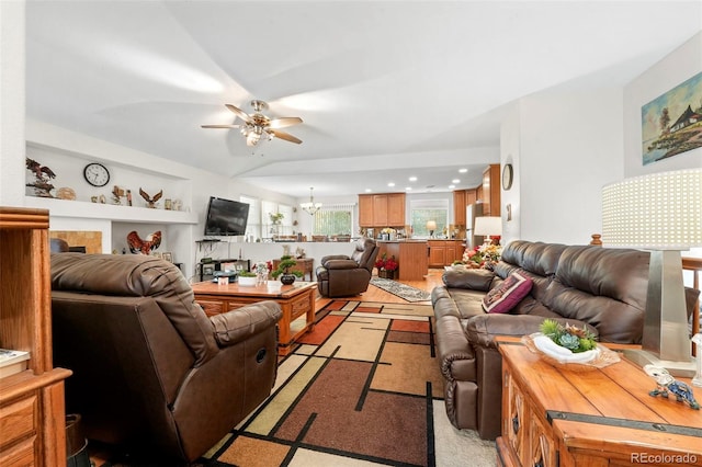 living room featuring ceiling fan with notable chandelier and light hardwood / wood-style floors