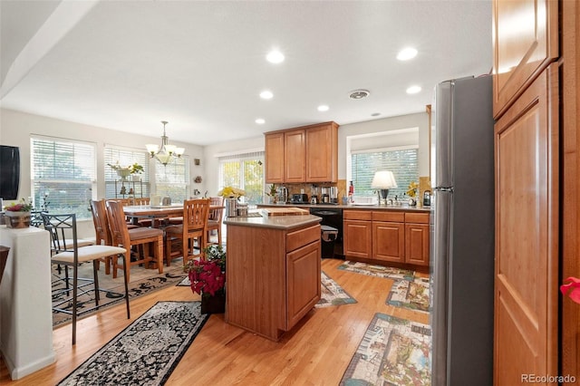 kitchen with stainless steel fridge, light wood-type flooring, decorative light fixtures, dishwasher, and a chandelier