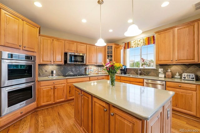 10705 Pinewalk Way, Highlands Ranch, CO 80130 - kitchen with stainless steel appliances, a sink, light wood-style floors, decorative backsplash, and pendant lighting