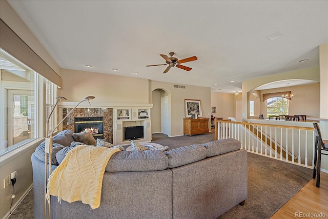 23425 E Otero Dr, Aurora, CO 80016 - living room featuring arched walkways, a ceiling fan, a high end fireplace, a chandelier, and wood finished floors