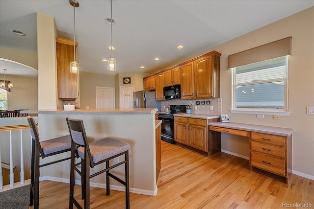 23425 E Otero Dr, Aurora, CO 80016 - kitchen featuring black appliances, healthy amount of natural light, a breakfast bar, backsplash, and recessed lighting