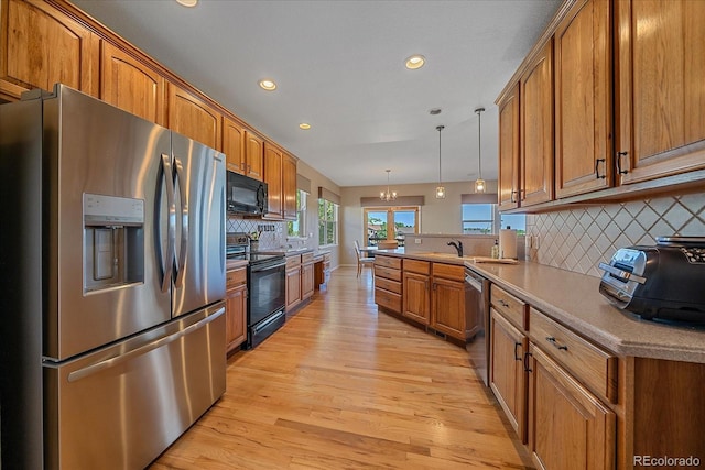 23425 E Otero Dr, Aurora, CO 80016 - kitchen featuring black appliances, brown cabinets, light wood-style flooring, a peninsula, and backsplash