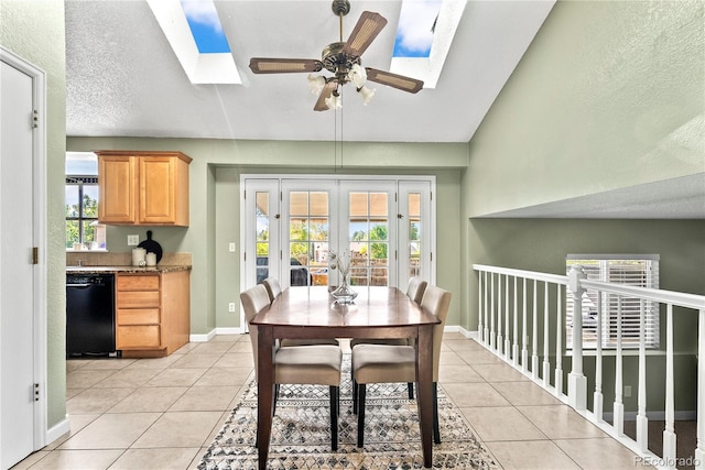 dining room featuring a textured ceiling, light tile patterned floors, lofted ceiling with skylight, ceiling fan, and french doors