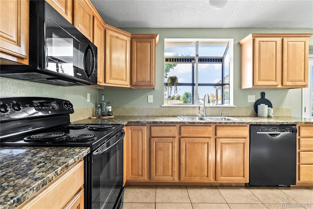 kitchen with a textured ceiling, sink, black appliances, light tile patterned floors, and dark stone countertops