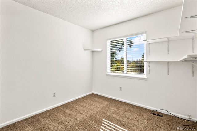 carpeted empty room with a textured ceiling