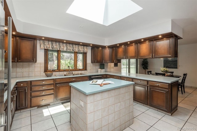 kitchen featuring light tile patterned floors, plenty of natural light, a sink, and a center island
