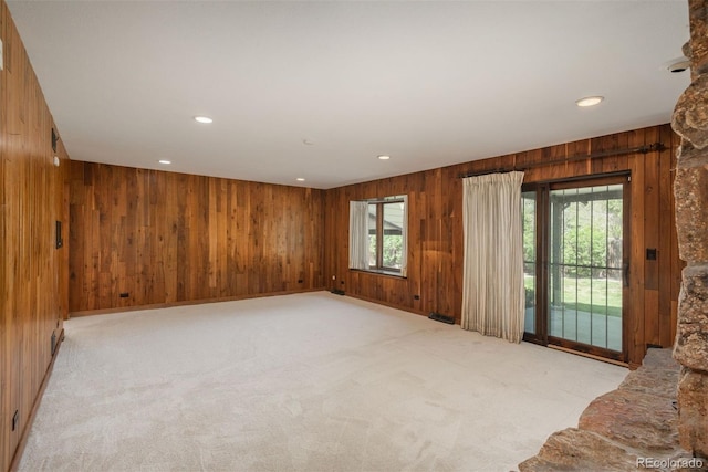unfurnished living room with wooden walls, recessed lighting, carpet floors, and a wealth of natural light