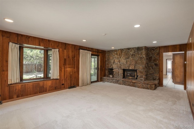 unfurnished living room with visible vents, wood walls, a fireplace, light colored carpet, and recessed lighting