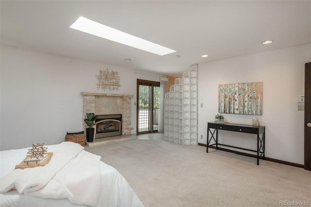 carpeted bedroom featuring a glass covered fireplace, access to exterior, baseboards, recessed lighting, and a skylight