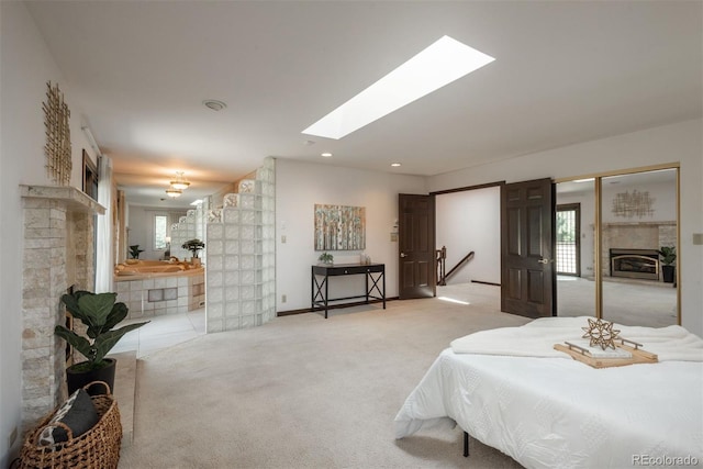 bedroom featuring recessed lighting, a glass covered fireplace, a skylight, and light carpet