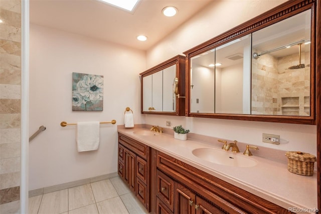 bathroom with double vanity, tile patterned floors, tiled shower, and a sink