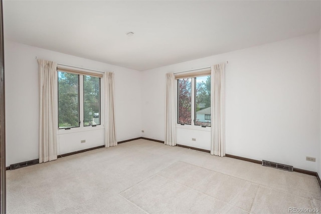 spare room featuring plenty of natural light, light carpet, and visible vents