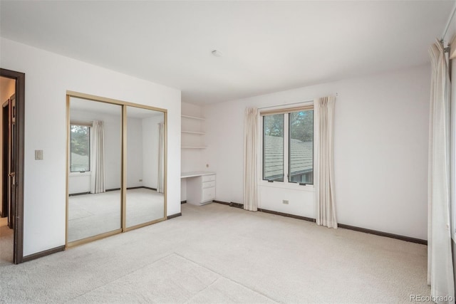unfurnished bedroom with baseboards, light carpet, and a closet