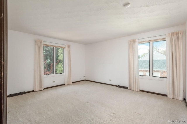 spare room featuring carpet floors, plenty of natural light, and visible vents
