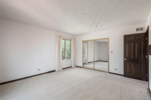 unfurnished bedroom with baseboards, visible vents, carpet, and a closet