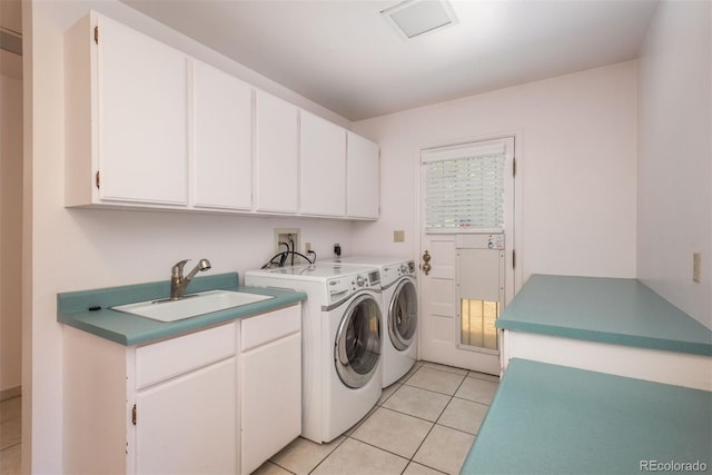 washroom with a sink, cabinet space, light tile patterned floors, and washing machine and clothes dryer