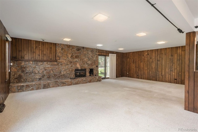 unfurnished living room featuring carpet floors, wood walls, and a fireplace