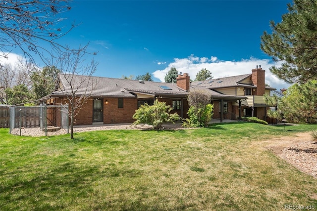 rear view of house with a lawn, fence, and brick siding