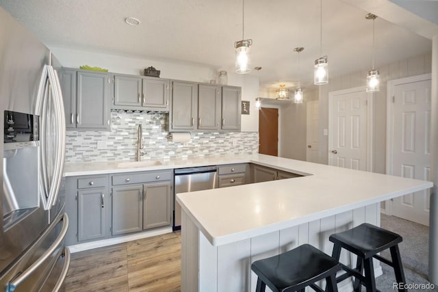 933 Straight Creek Dr Unit 101, Dillon, CO 80435 - kitchen featuring gray cabinetry, a sink, a kitchen bar, a peninsula, and appliances with stainless steel finishes