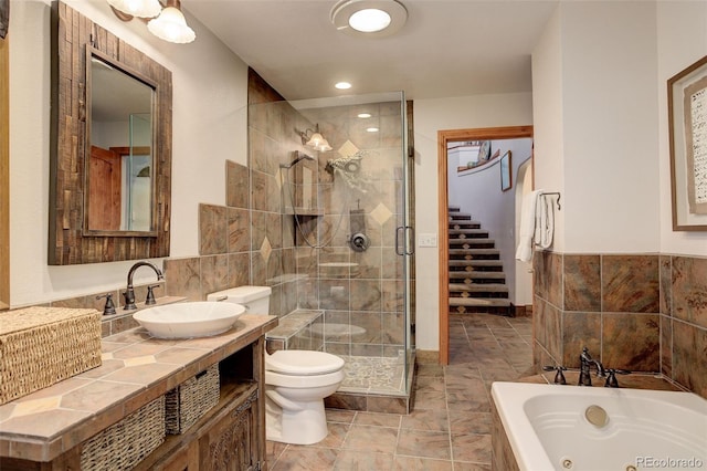 full bathroom featuring shower with separate bathtub, vanity, toilet, and tile walls