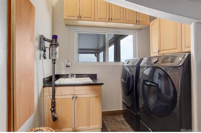 washroom with sink, dark tile patterned floors, cabinets, and independent washer and dryer