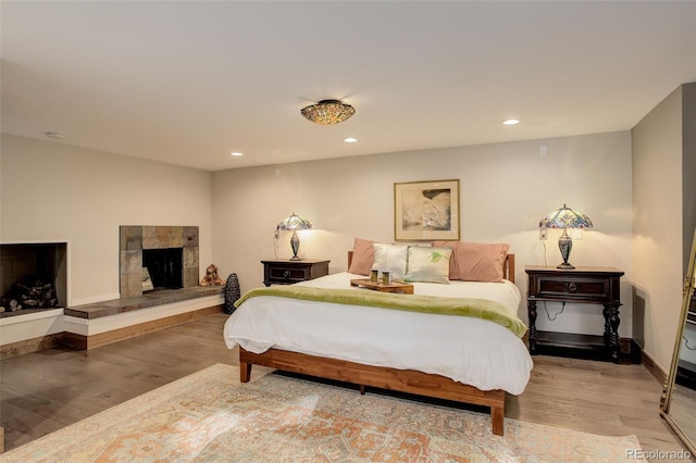 bedroom featuring a tile fireplace and hardwood / wood-style flooring