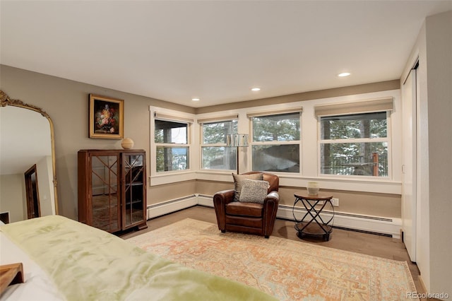 living area with a healthy amount of sunlight, wood-type flooring, and a baseboard heating unit