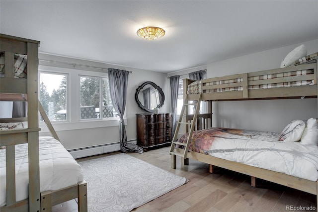 bedroom with light hardwood / wood-style flooring and a baseboard heating unit