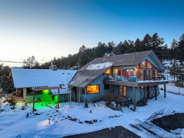 snow covered rear of property with a balcony