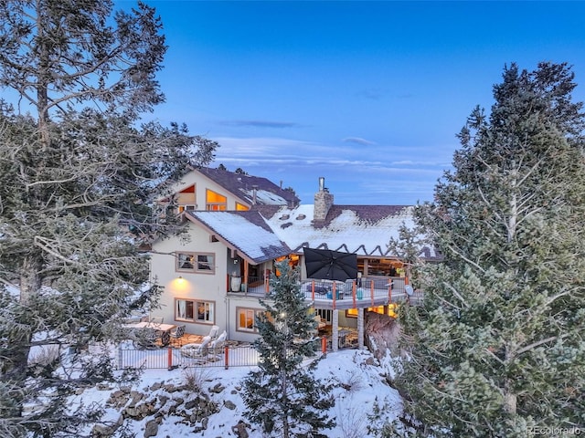 snow covered back of property with a balcony