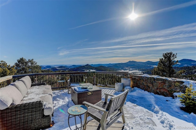 snow covered patio with a mountain view and outdoor lounge area