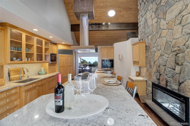 kitchen with exhaust hood, a stone fireplace, sink, dark hardwood / wood-style floors, and light stone countertops