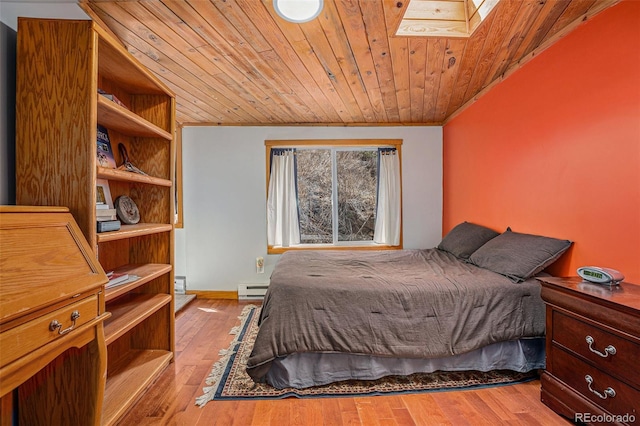 bedroom with wood ceiling, light wood-type flooring, a skylight, crown molding, and a baseboard radiator