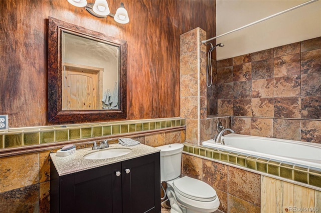 bathroom featuring toilet, a relaxing tiled tub, and vanity