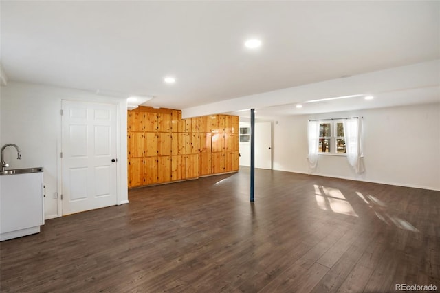 basement featuring dark hardwood / wood-style floors, wood walls, and sink