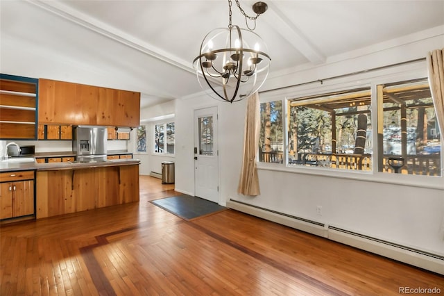 kitchen featuring sink, beamed ceiling, a baseboard heating unit, stainless steel fridge, and a chandelier