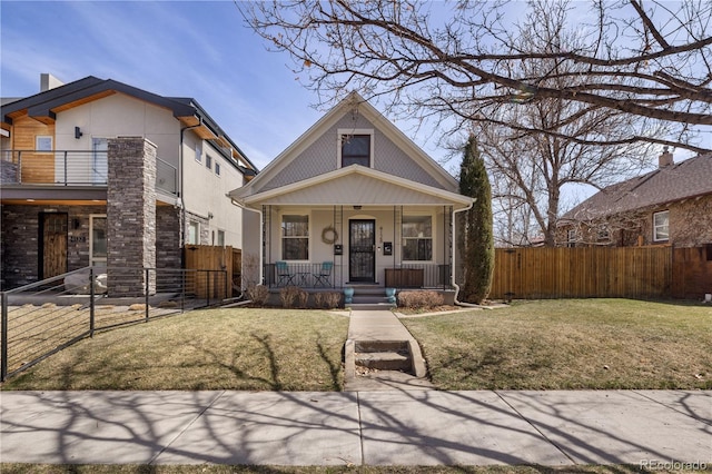 view of front of property featuring a front lawn, a balcony, fence, and covered porch