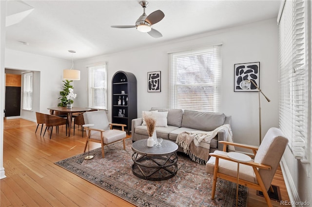 living room featuring crown molding, light wood-style floors, visible vents, and ceiling fan