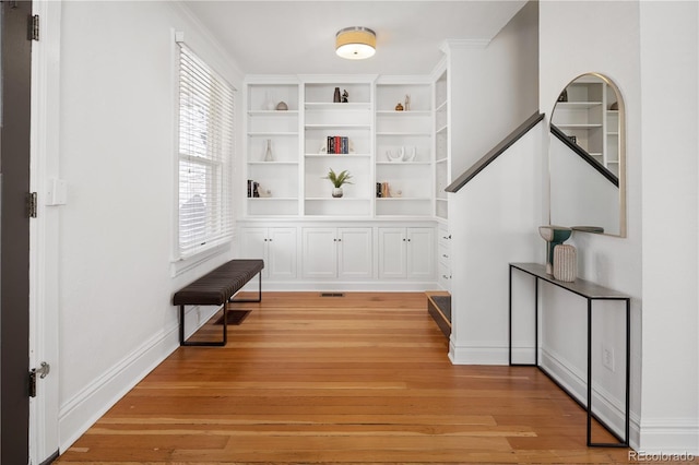 hall featuring built in features, baseboards, and light wood-style flooring