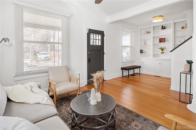 living room featuring baseboards, light wood-style floors, and crown molding