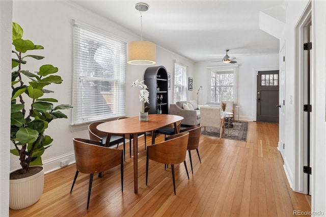 dining area with baseboards, a ceiling fan, and light wood finished floors